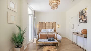 A room with a bed, a potted plant, a wooden coffee table, and a painting on the wall.