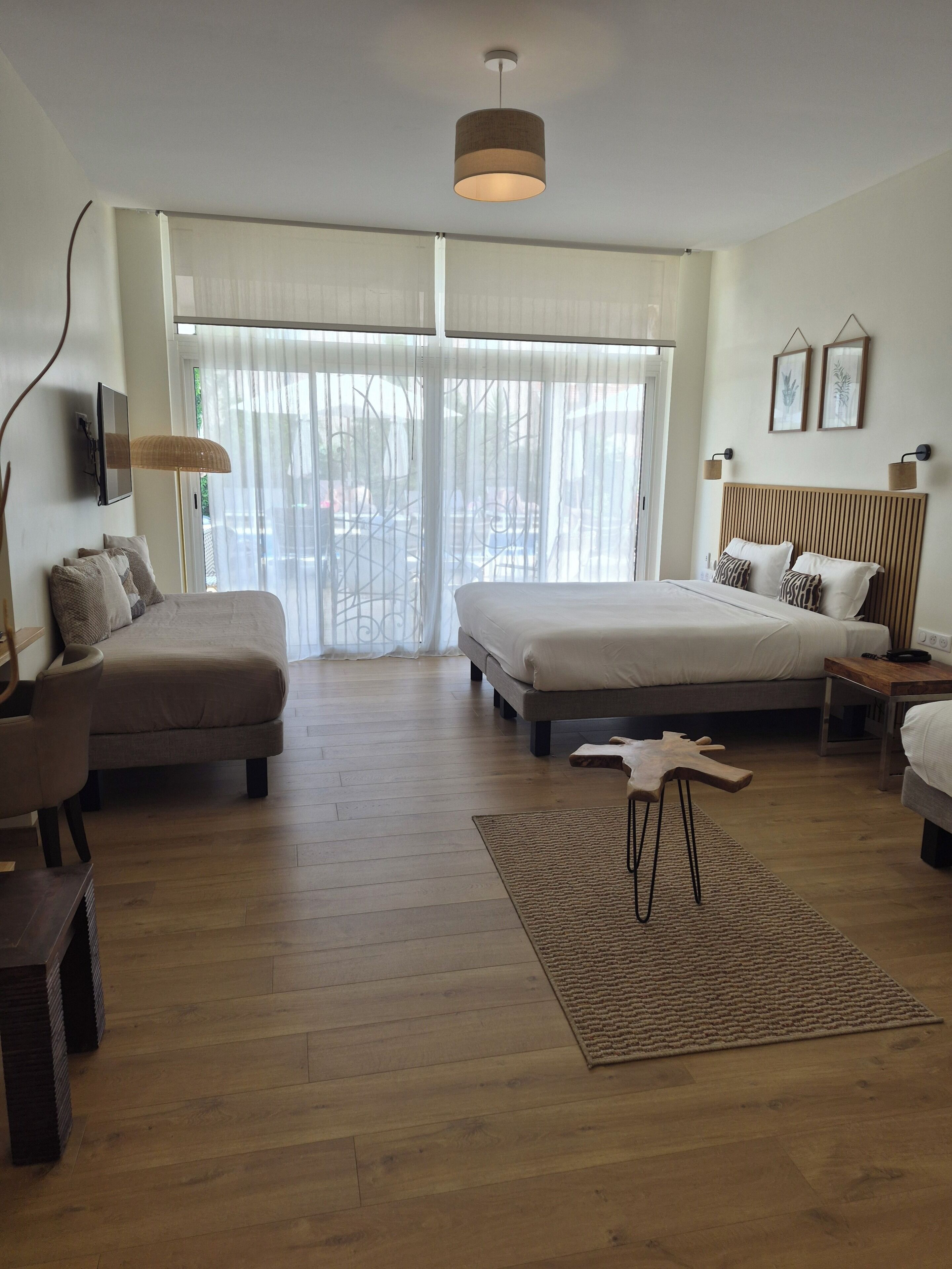 A modern bedroom with a large bed, a sofa, a desk, and a TV.