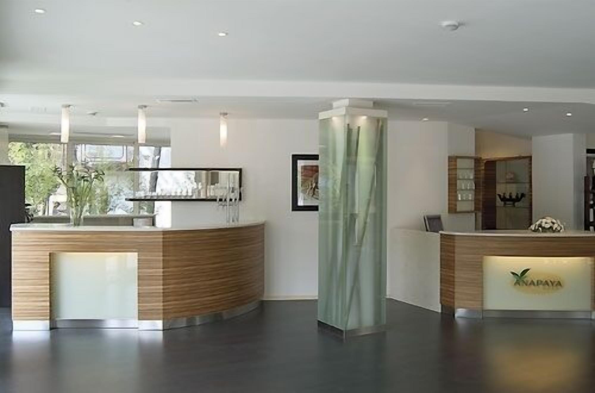 A reception area with a wooden reception desk, a green pillar, and a framed picture on the wall.