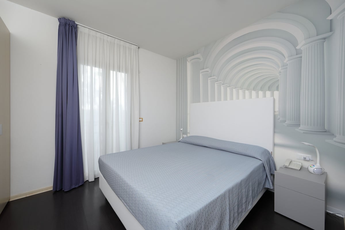 Een moderne slaapkamer met een bed, nachtkastje en inbouwkasten.