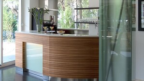 A modern kitchen with a wooden countertop, stainless steel appliances, and a glass partition. - Hotel Anapaya (Lignano Sabbiadoro)