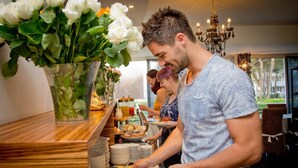 A buffet setup with various food items and a decorative vase of white flowers. - Hotel Anapaya (Lignano Sabbiadoro)