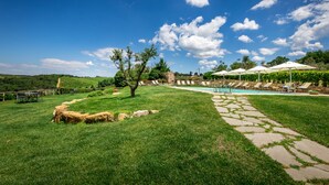 Un patio trasero con piscina, sillas de descanso y un camino de piedra.
