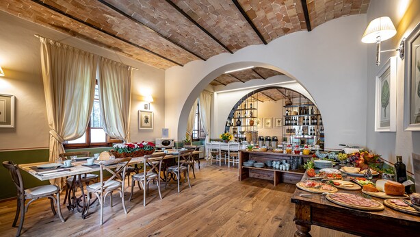 Un comedor con mesas y sillas de madera, techo de ladrillo y una alacena para vinos al fondo.