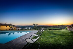 Ein Poolbereich mit Liegestühlen, blauem Himmel und Blick ins Umland.