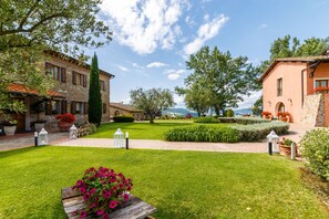 A well-maintained garden with a paved walkway, stone buildings, and a clear view of the surrounding landscape. - Tenuta Quadrifoglio (Gambassi Terme)