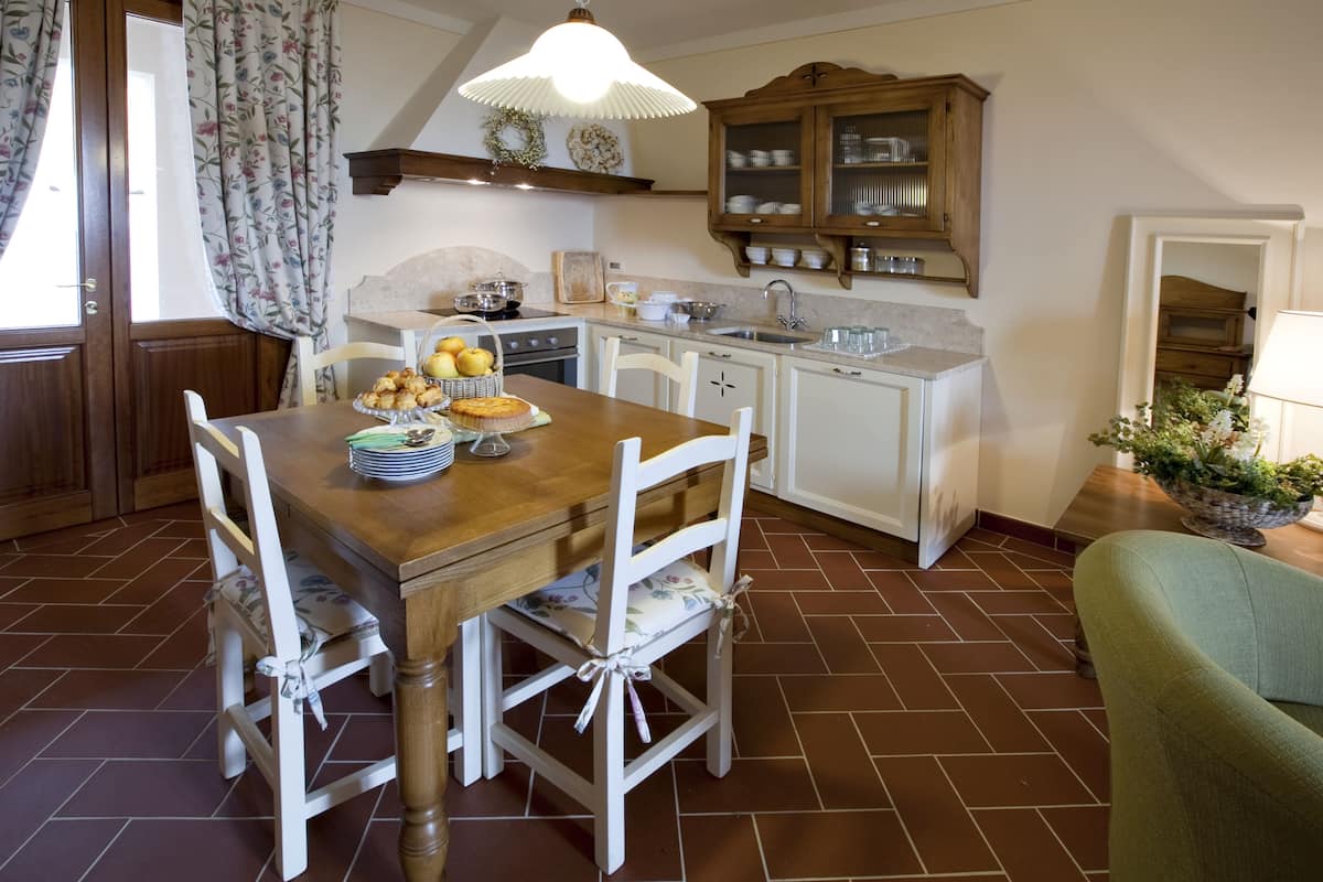 A kitchen with a wooden table, white chairs, a sink, and a cabinet.