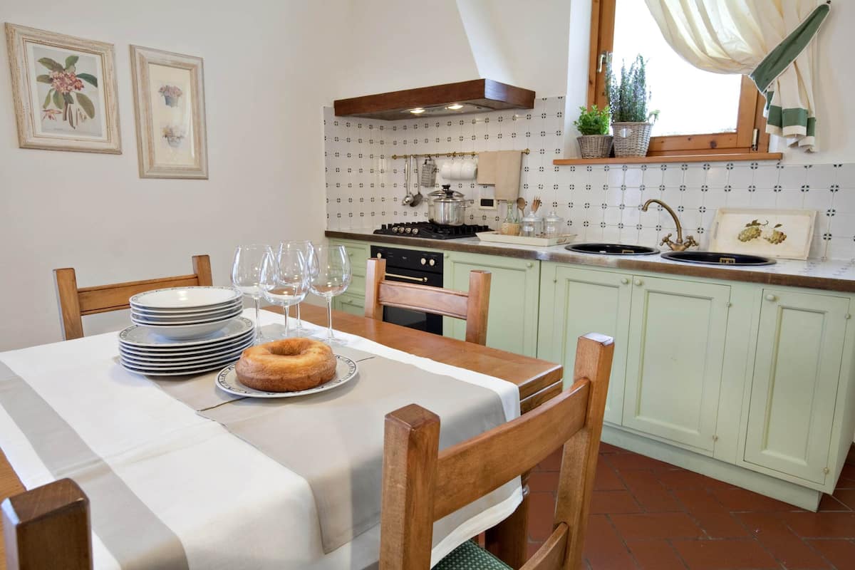 A kitchen with a dining table set for four, a stove, and a sink.