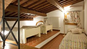 A bedroom with two beds, a wooden ceiling, and a tiled floor.