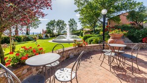 An outdoor patio with tables and chairs, a fountain, and a well-maintained garden. - Tenuta Quadrifoglio (Gambassi Terme)