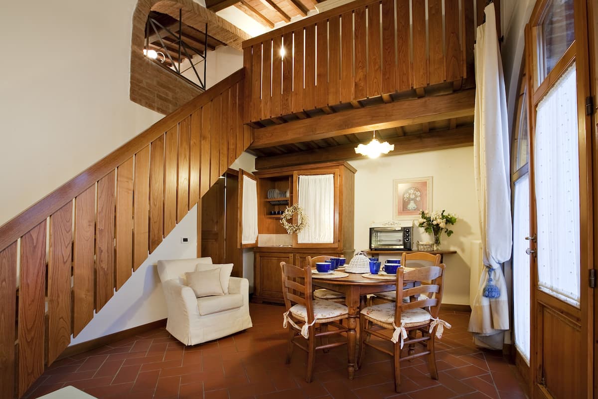 A dining area with a wooden staircase, a white sofa, and a dining table with chairs.