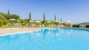 A swimming pool with lounge chairs and umbrellas, surrounded by greenery and trees. - Tenuta Quadrifoglio (Gambassi Terme)