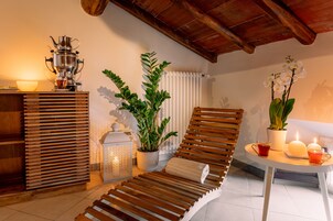 Una stanza luminosa con una poltrona in legno, un tavolo con una candela, una pianta in vaso e un set da tè tradizionale.