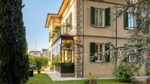 Un edificio a due piani con un balcone, piante in vaso e cielo sereno.