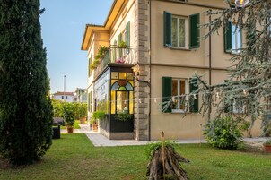 Un edificio a due piani con un balcone, piante in vaso e cielo sereno.