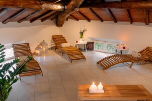 Un'ampia stanza con poltrone in legno, un tavolino con candele e vista sull'esterno.