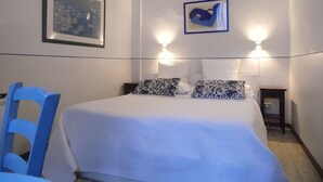 Une chambre à coucher comprenant un lit, une chaise, deux lampes fixées au mur et deux tableaux encadrés.