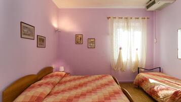 Una habitació amb dos llits, una finestra amb cortines i quadres a la paret.