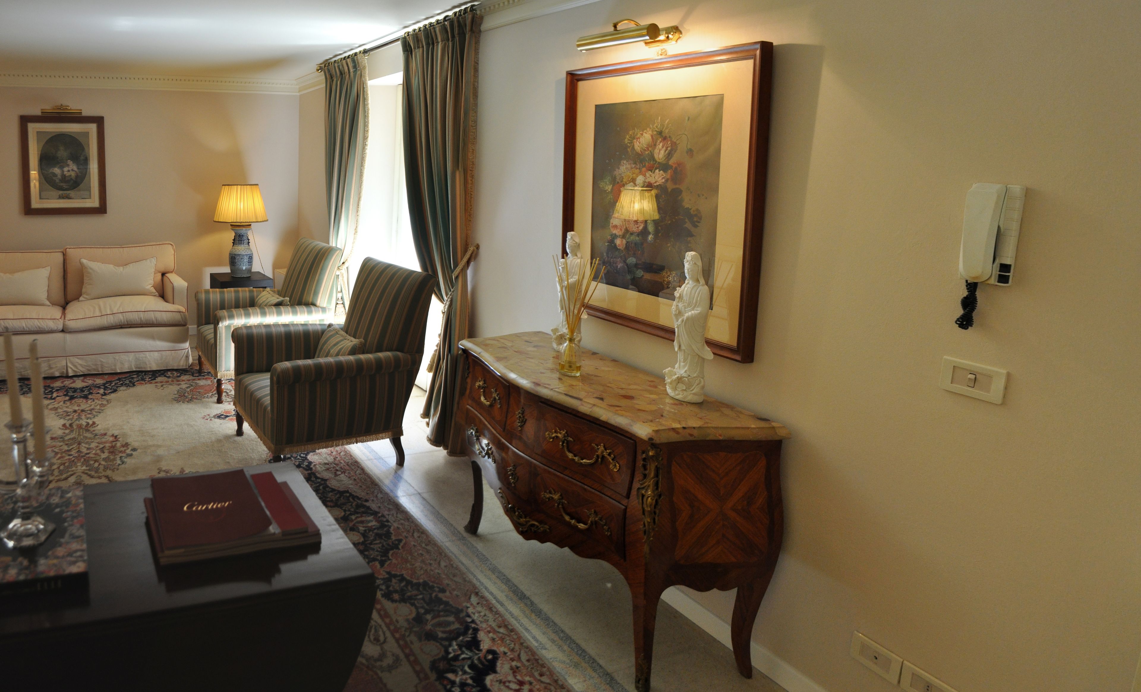 A living room with a sofa, armchair, and a wooden side table with a lamp and a statue.
