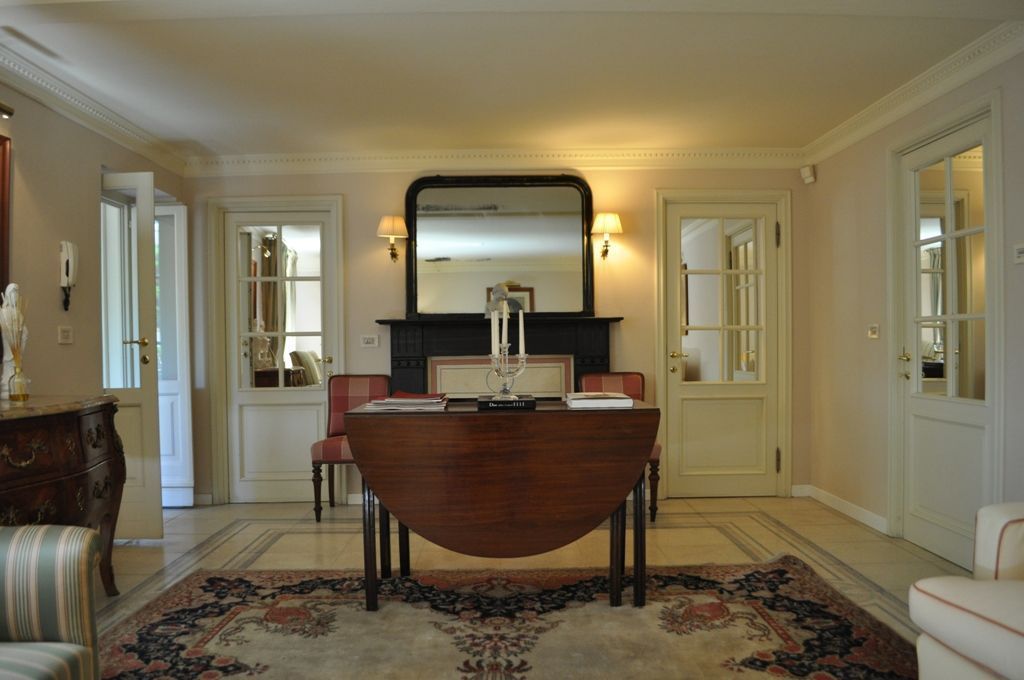 A formal room with a dark wooden table, a large mirror, and two chairs.