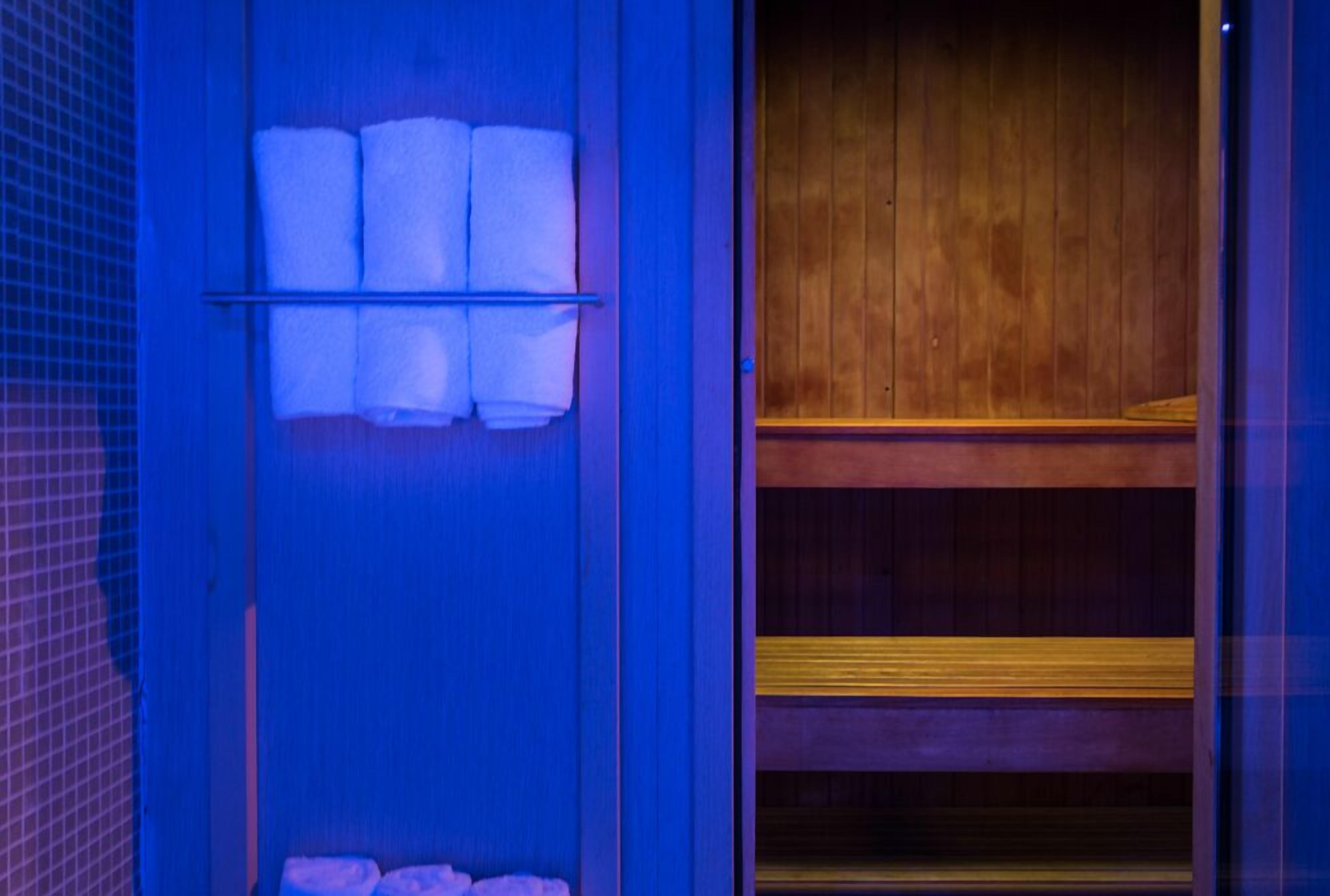 Un baño con pared azul, un banco de madera y un estante con toallas.