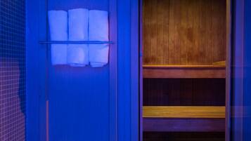 Un baño con pared azul, un banco de madera y un estante con toallas.