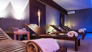 Un'area spa con lettini in legno, un tavolo da massaggio e una parete con effetto camino.