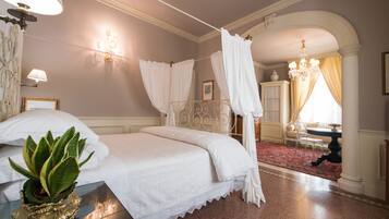 Een slaapkamer met een hemelbed, een kroonluchter en een groot raam met gordijnen.