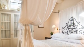 Una camera da letto con un letto a baldacchino, soffitto in legno e pavimento a spina di pesce.