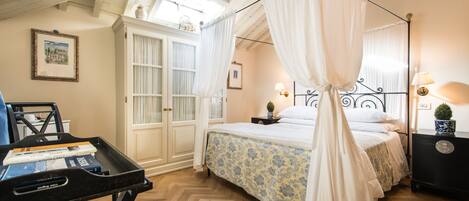 Un dormitorio con cama con dosel, un escritorio con silla y una ventana con cortinas.