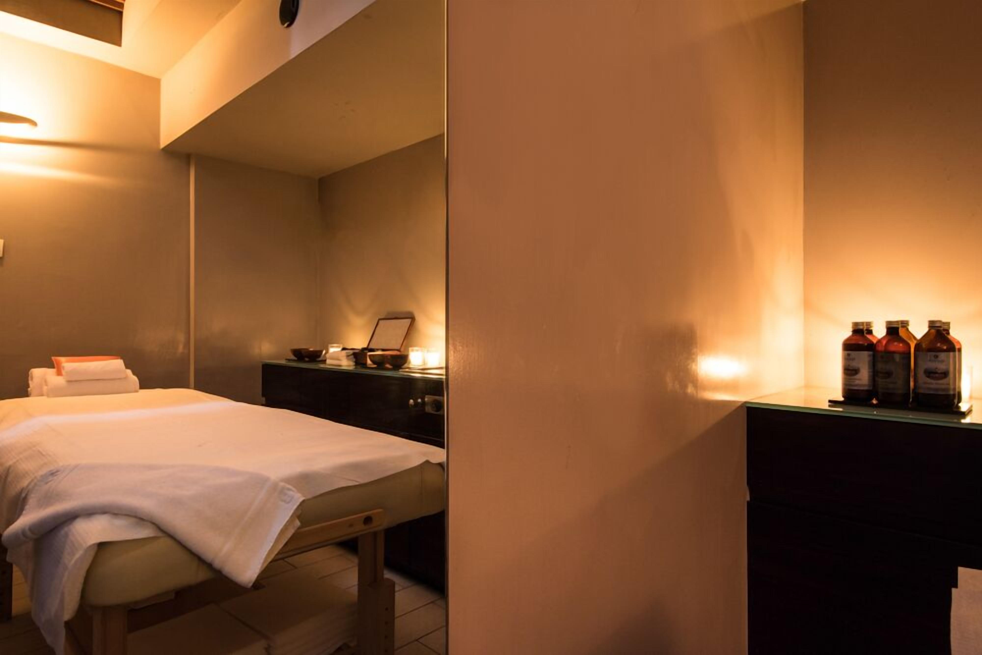 Une chambre d’hôtel avec un lit, une table de chevet et un petit bureau sur lequel se trouvent des bouteilles.