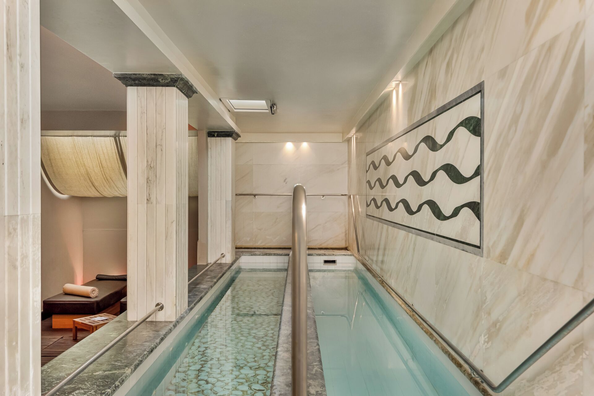 Un área de spa con piscina, sillón de masaje y pared con diseño ondulado.