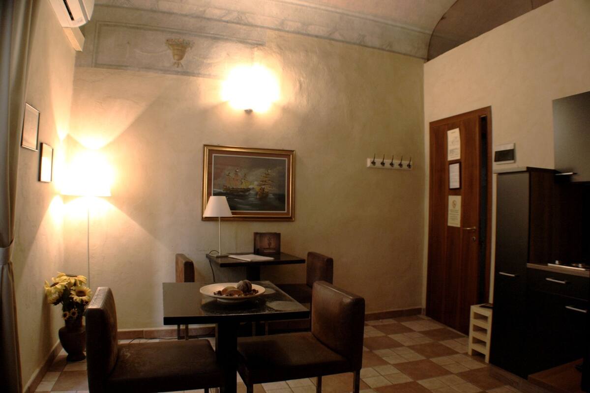 Un espace repas comprenant une table, des chaises, un tableau et un luminaire fixé au mur.