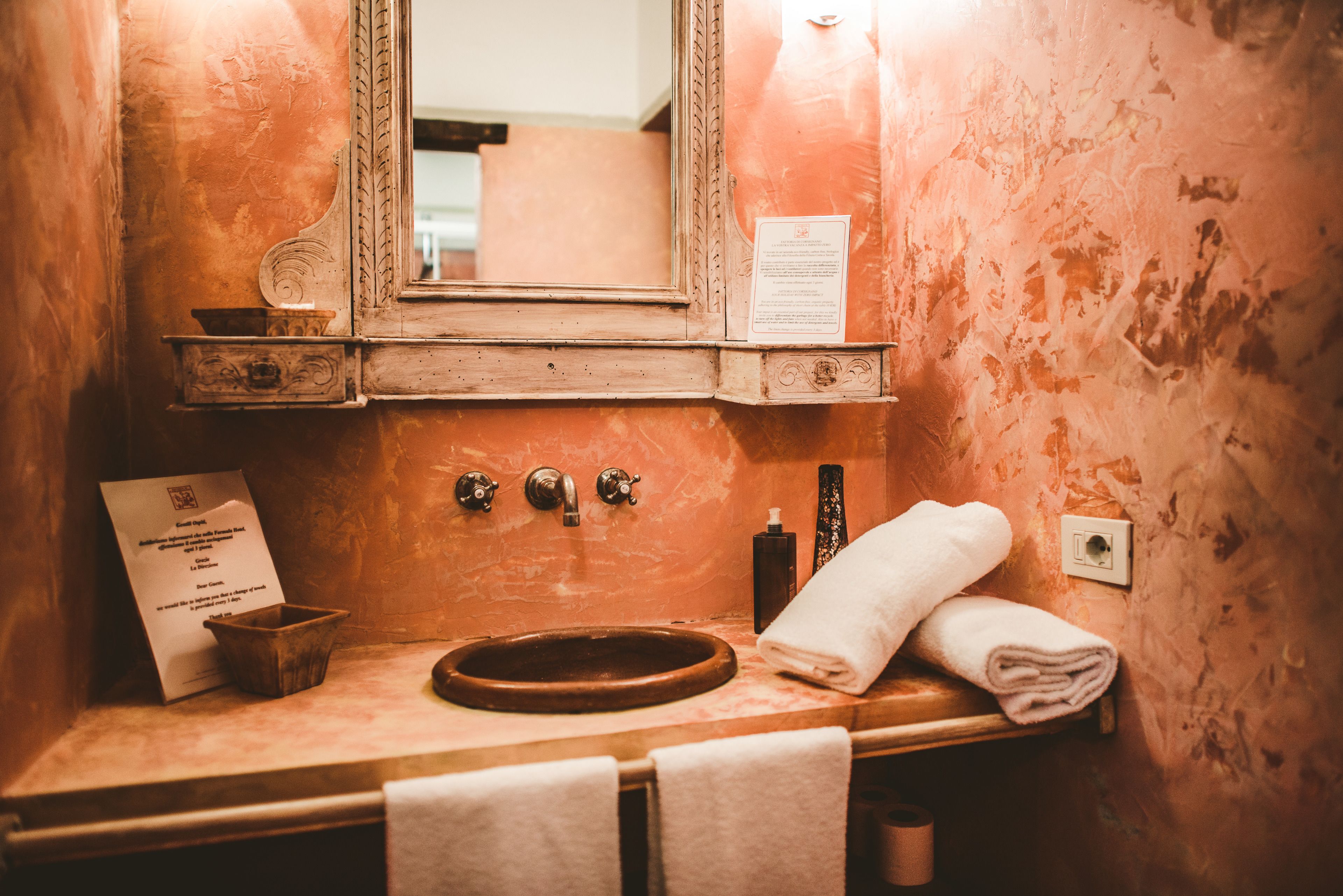 Une salle de bain au style rétro, avec un lavabo en bois, deux robinets, un miroir et une serviette.