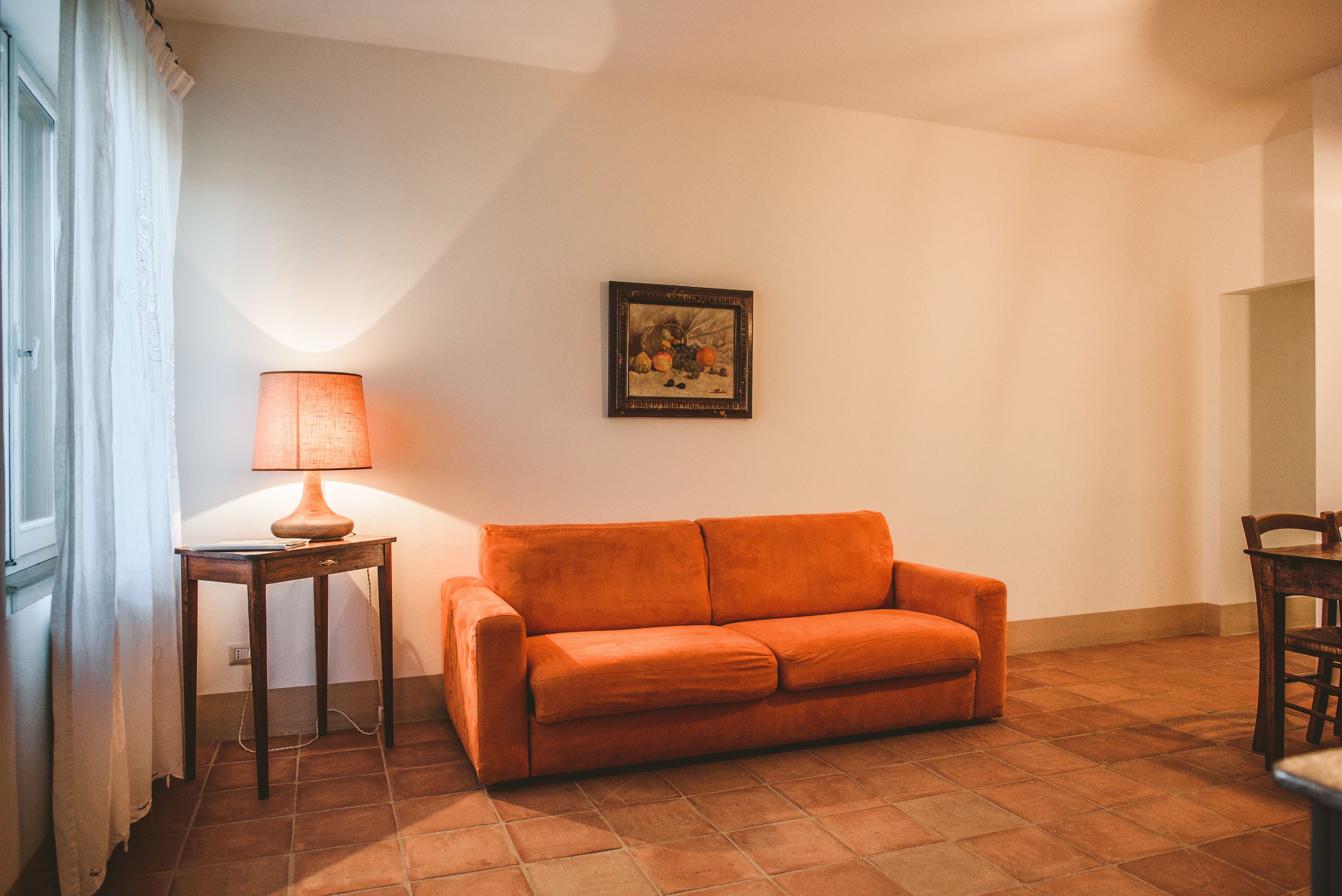 Una sala de estar con un sofá, una lámpara y un cuadro en la pared.