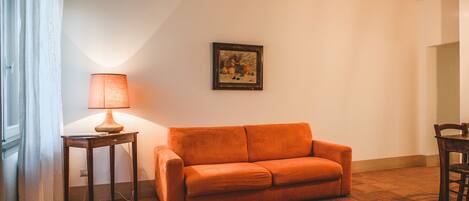 Una sala de estar con un sofá, una lámpara y un cuadro en la pared.