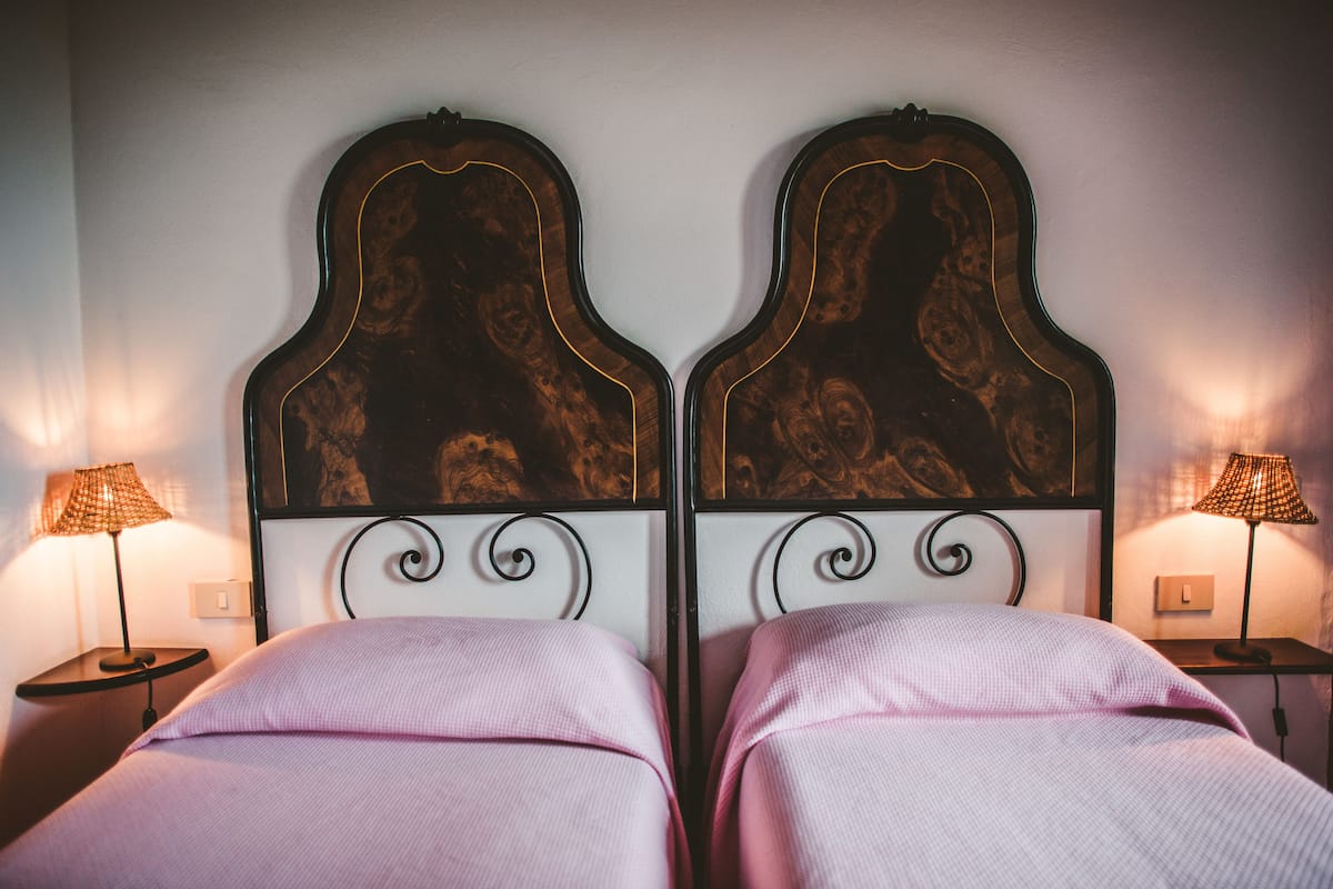 Ein Zimmer mit zwei Betten, jeweils mit Kopfstücken und Nachttischlampen.