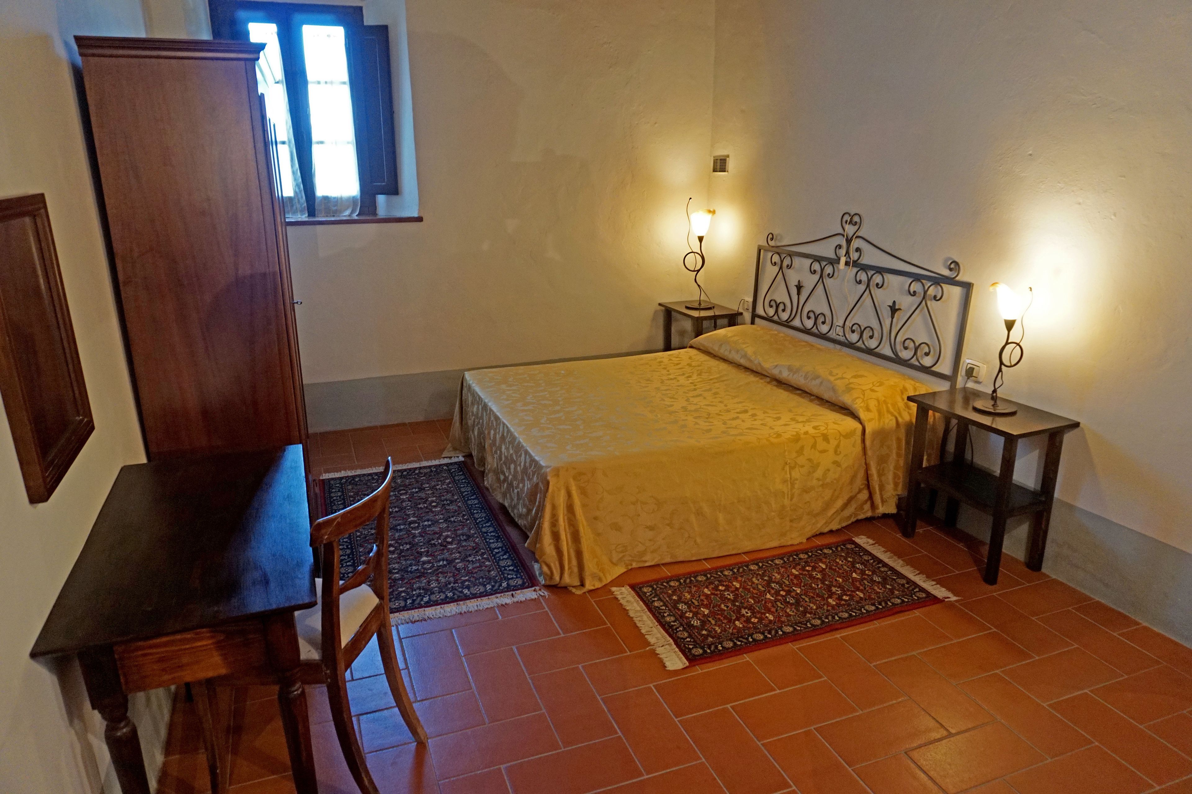 A bedroom with a bed, bedside tables, a desk, and a chair.
