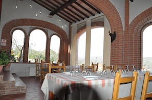 Ein Restaurant mit Backsteinbögen, Außenplätzen und Blick auf die Landschaft.