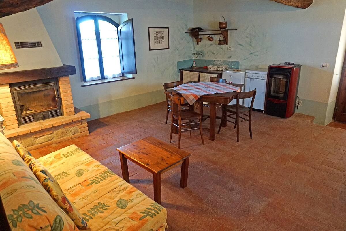 Un salon chaleureux avec une cheminée, une table à manger avec des chaises, un canapé et un coin cuisine équipé d’un réfrigérateur et d’une cuisinière.