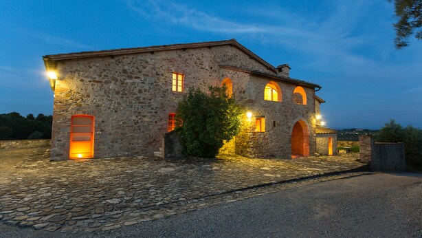A stone building with multiple windows and a door, illuminated by warm lighting. - Tenuta di Monaciano (Castelnuovo Berardenga)