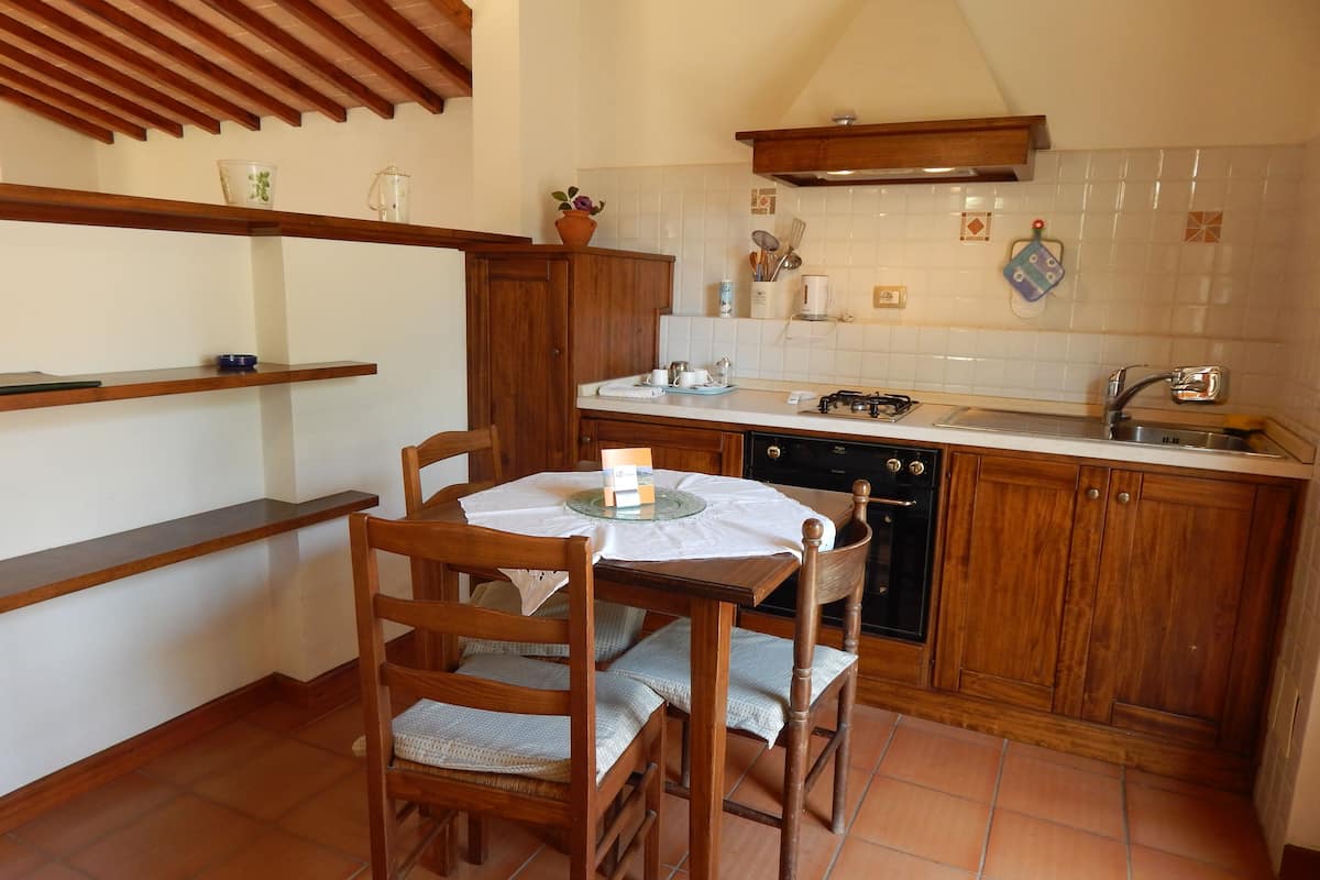 Una cocina compacta con armarios de madera, una mesa de comedor con sillas y un salpicadero de azulejos.