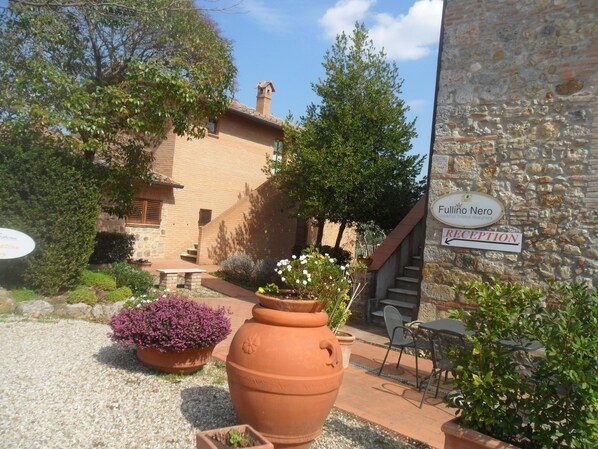 A reception area with a stone wall, a sign for 'Fulliino Nero', and outdoor seating. - Fullino Nero (Siena)