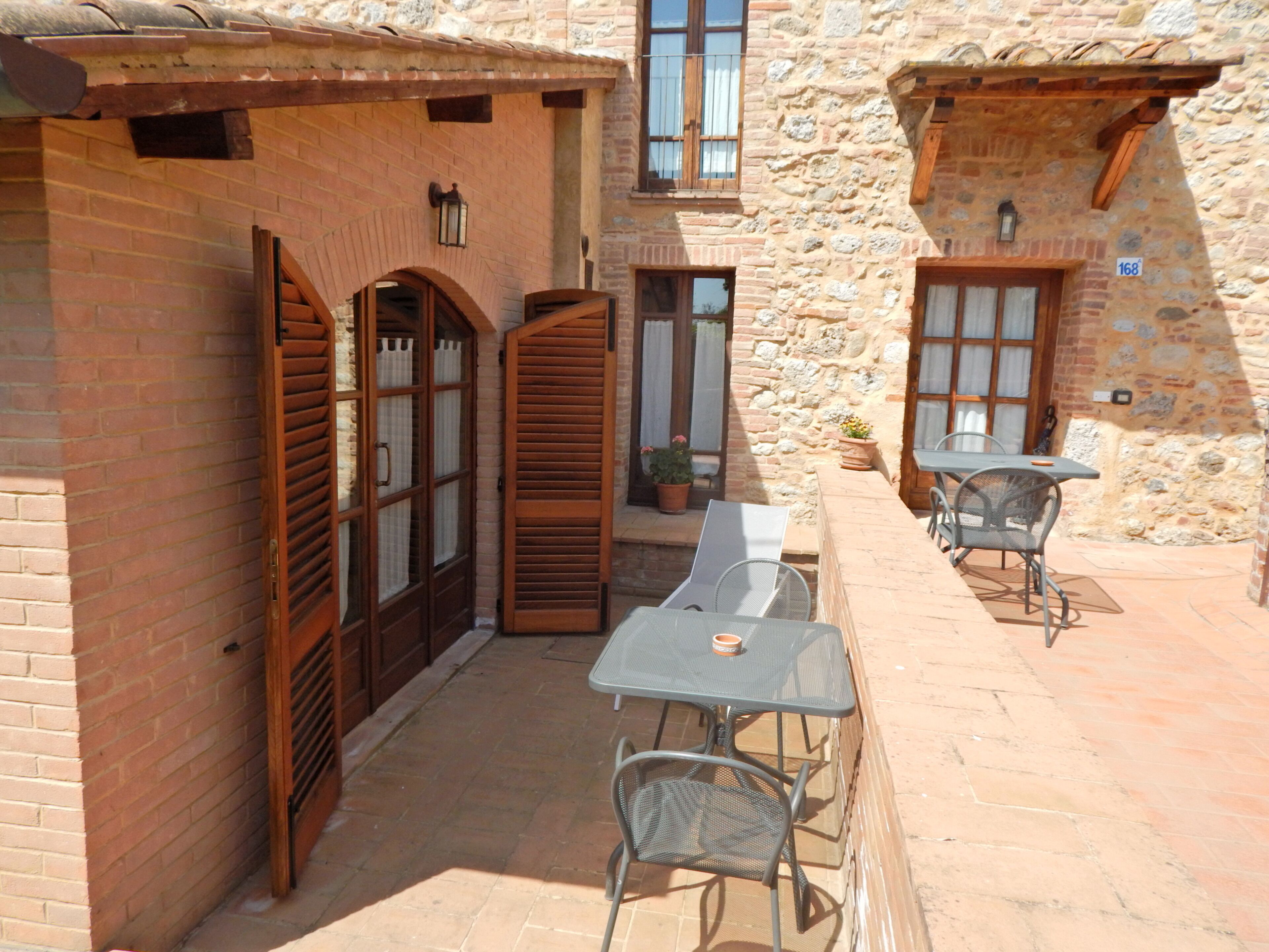 A courtyard with a table and chairs, a wooden door, and a stone wall.