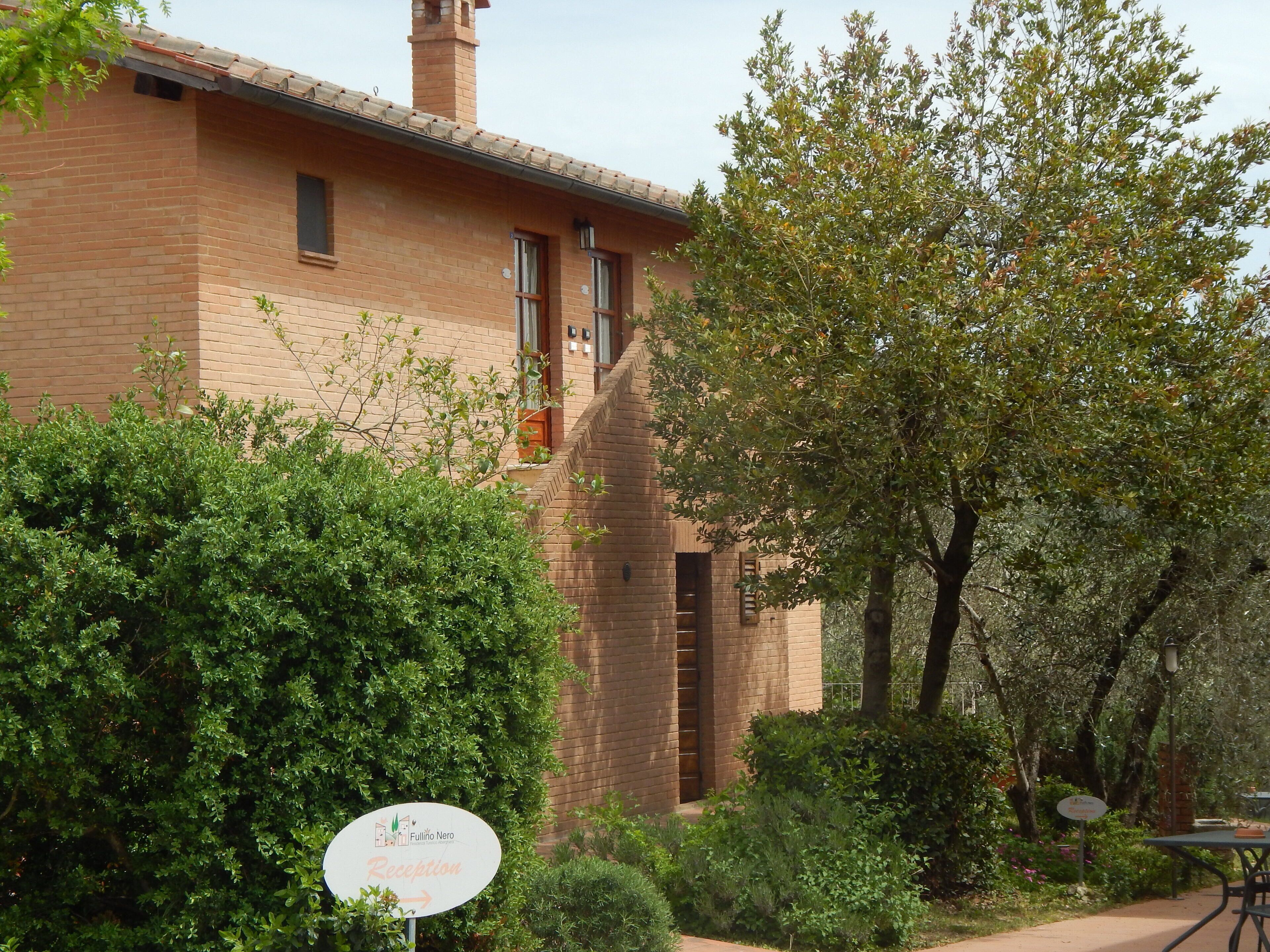 A reception area with a sign indicating 'Fullino Nero' and a brick building with windows and a chimney.