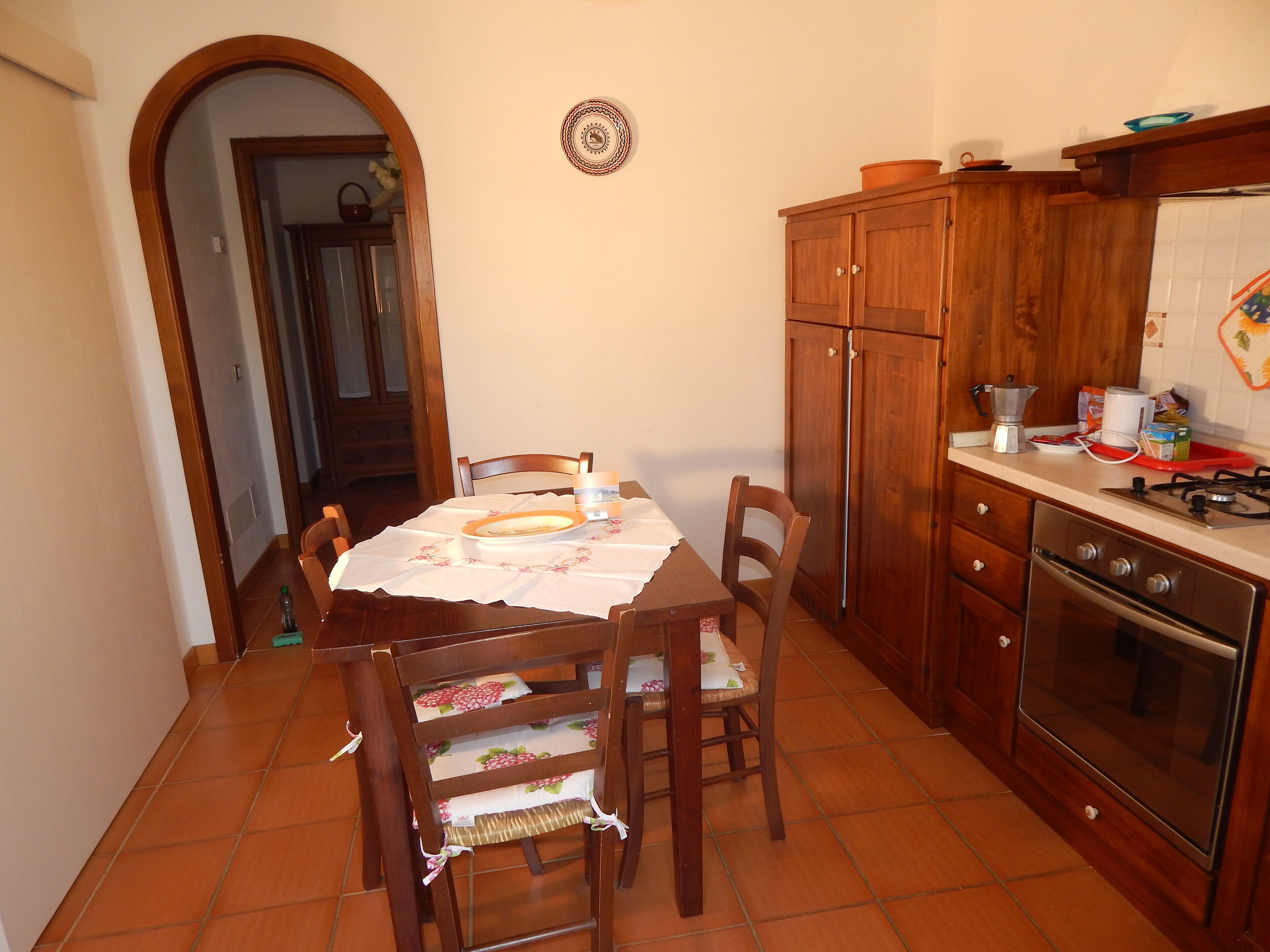 A kitchen with wooden cabinets, a gas stove, and a dining table with chairs.