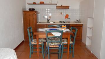 Une cuisine de taille réduite comprenant une table à manger, des chaises et un petit plan de travail.