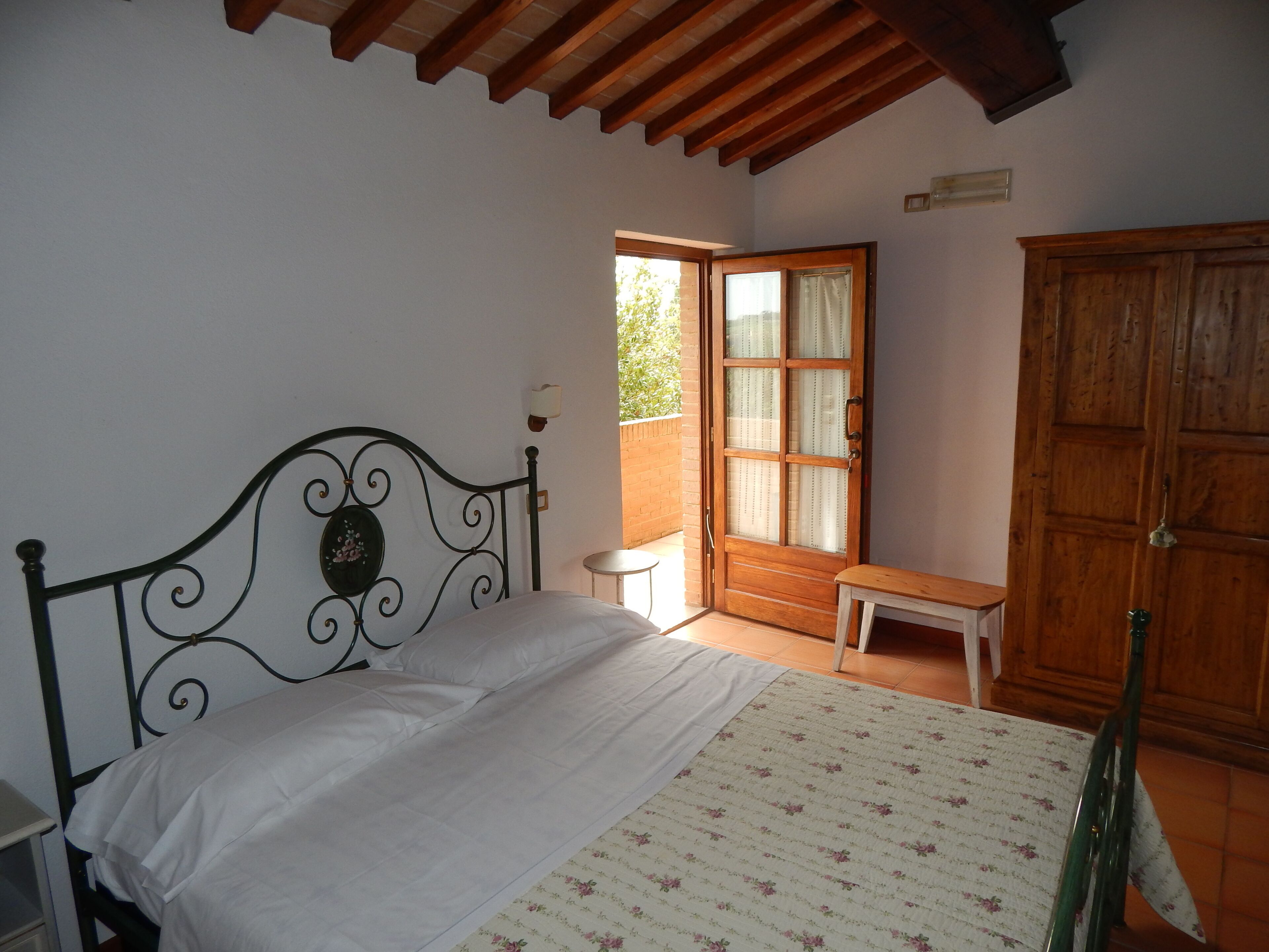 Une chambre à coucher avec un lit, une armoire en bois, un banc et une petite table.