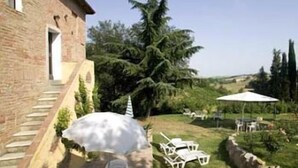 A brick building with a patio area featuring outdoor furniture and umbrellas. - La Grotta di Montecchino (Siena)