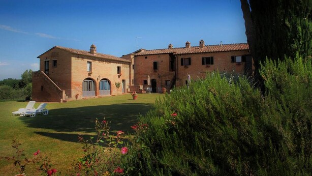 A large brick building with a well-maintained lawn and outdoor seating area. - La Grotta di Montecchino (Siena)